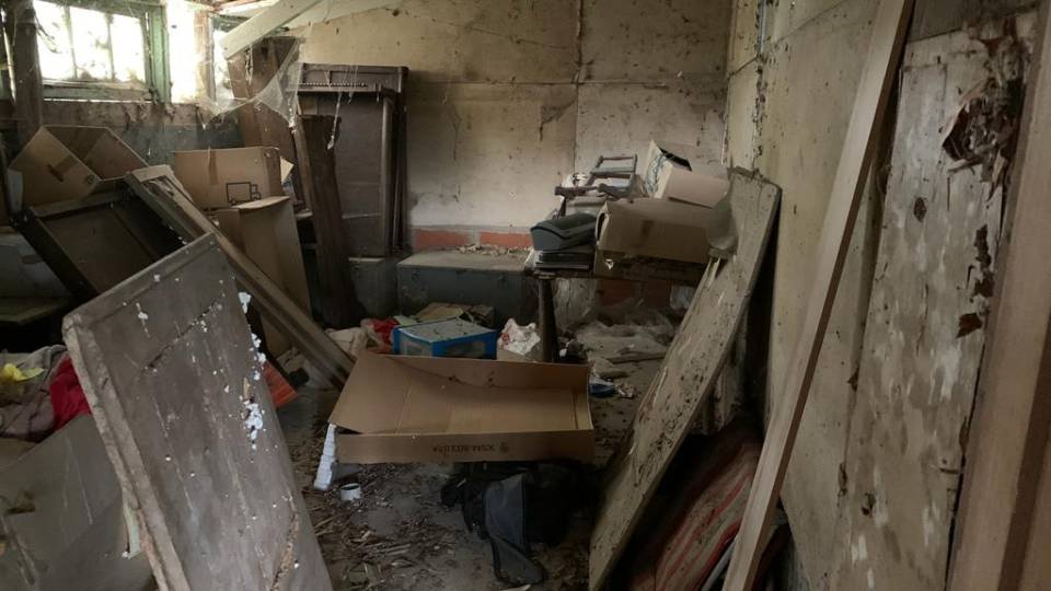Débarras d'un hangar, pièce pleine de bois et cartons, déchets divers et sale avant